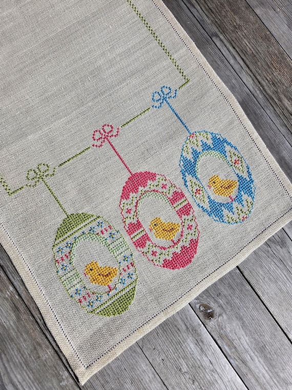 Korsstygn på en linnefärgad löpare med motiv av gula kycklingar i påskägg.